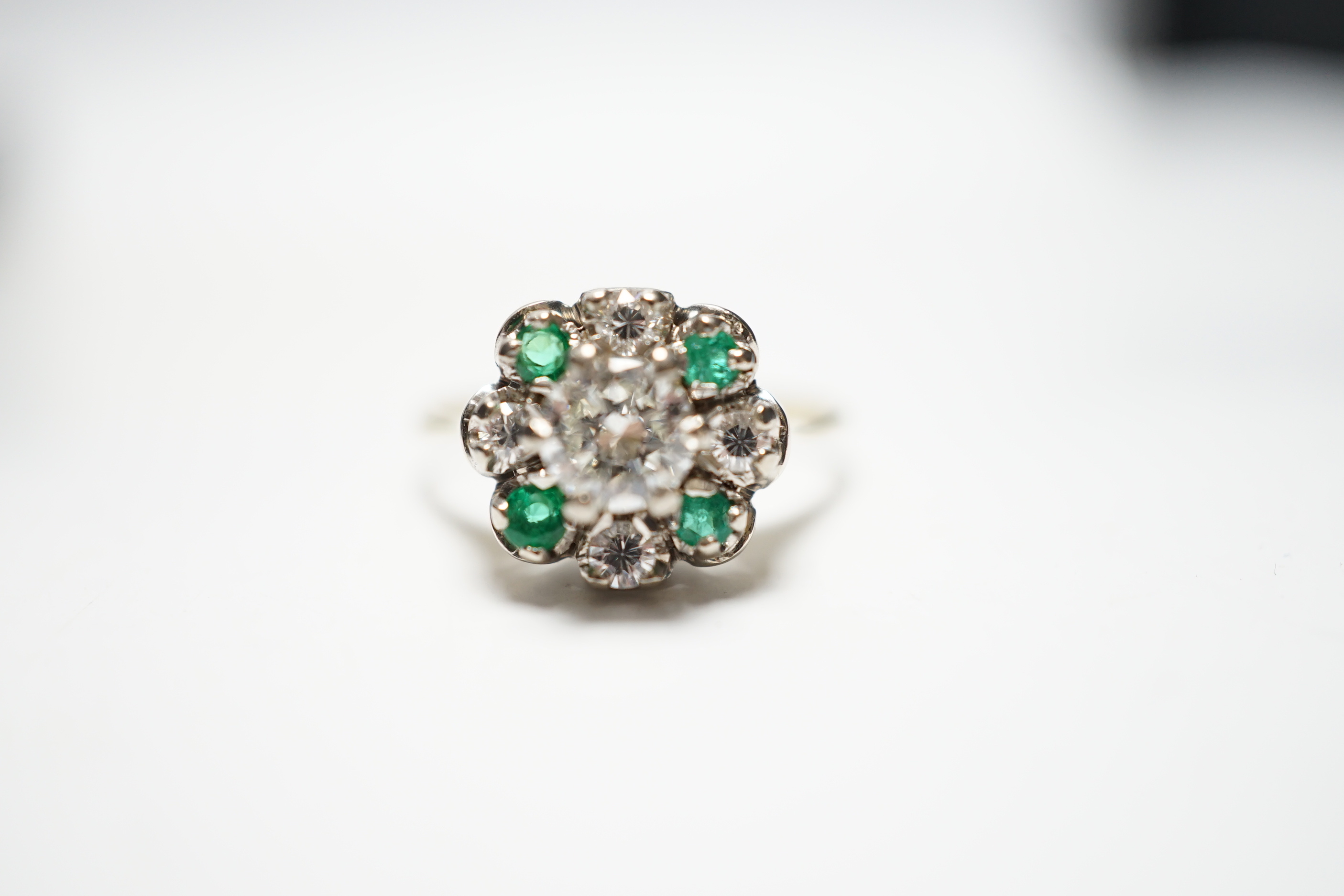 A yellow metal, diamond and emerald set flower head cluster ring, size P, gross weight 4 grams, the central diamond measuring approximately 5.5mm in diameter.
